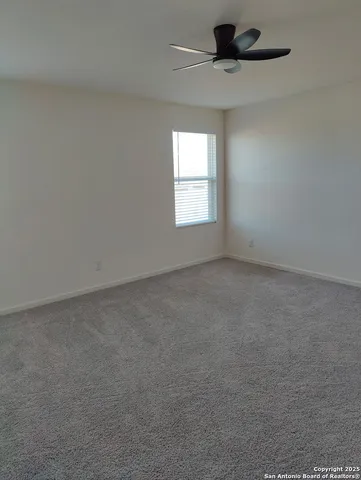an empty room with a window and a ceiling fan