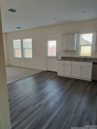 a kitchen with granite countertop wooden floors and wide window
