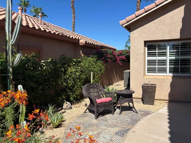 a backyard of a house with table and chairs plants