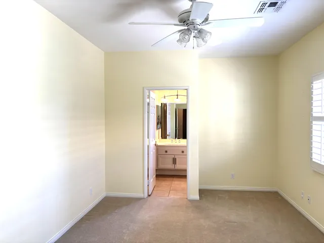 a view of a livingroom with a chandelier fan and kitchen view