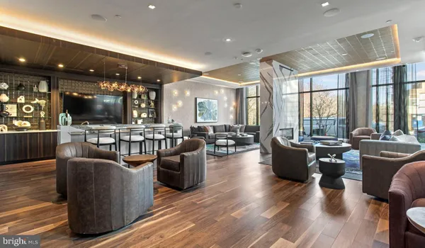 a living room with couches a coffee table and kitchen view with wooden floor