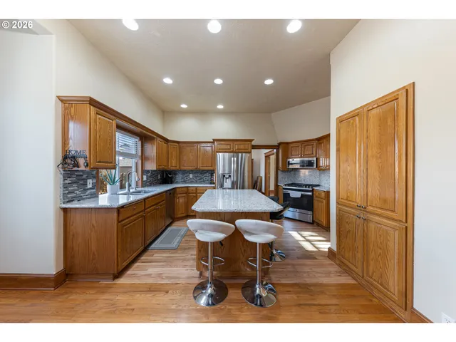 a kitchen with stainless steel appliances kitchen island granite countertop a refrigerator a stove a sink dishwasher with a dining table and chairs