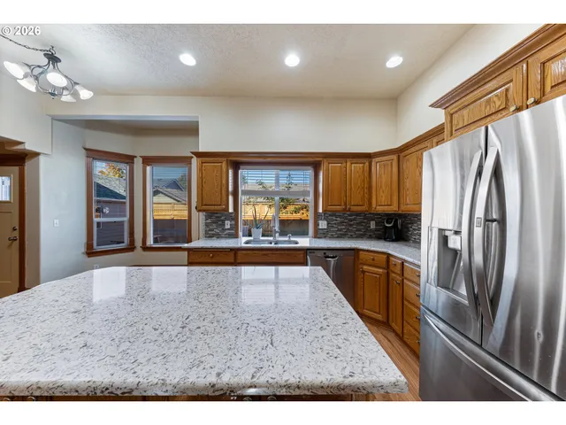 a large kitchen with stainless steel appliances granite countertop a refrigerator and a sink