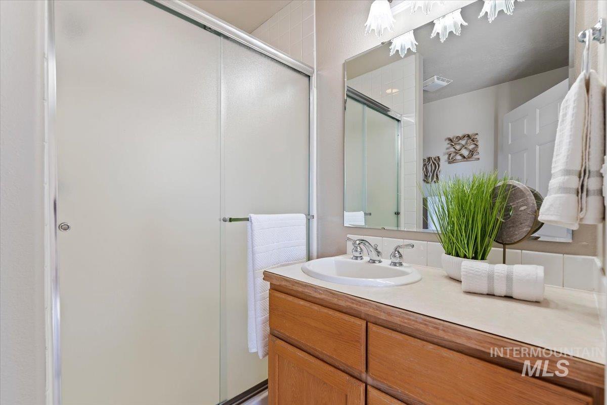 147 East Indian Crk Road Boise, ID 83716 - Photo 23 of 43 Built-in vanity with a single basin sink and chrome faucet, featuring a large mirror and overhead decorative lighting
