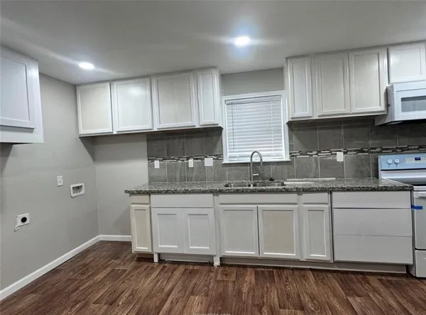a kitchen with granite countertop wooden cabinets a sink and dishwasher