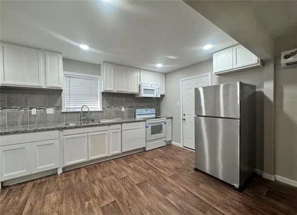 a kitchen with granite countertop stainless steel appliances a refrigerator a sink and cabinets