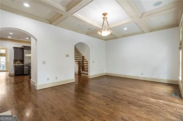 an empty room with wooden floor chandelier and entryway