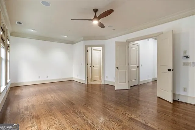 an empty room with wooden floor ceiling fan and windows