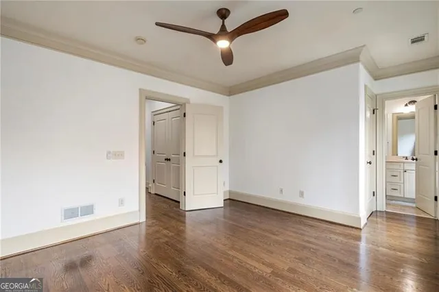 an empty room with wooden floor and a ceiling fan
