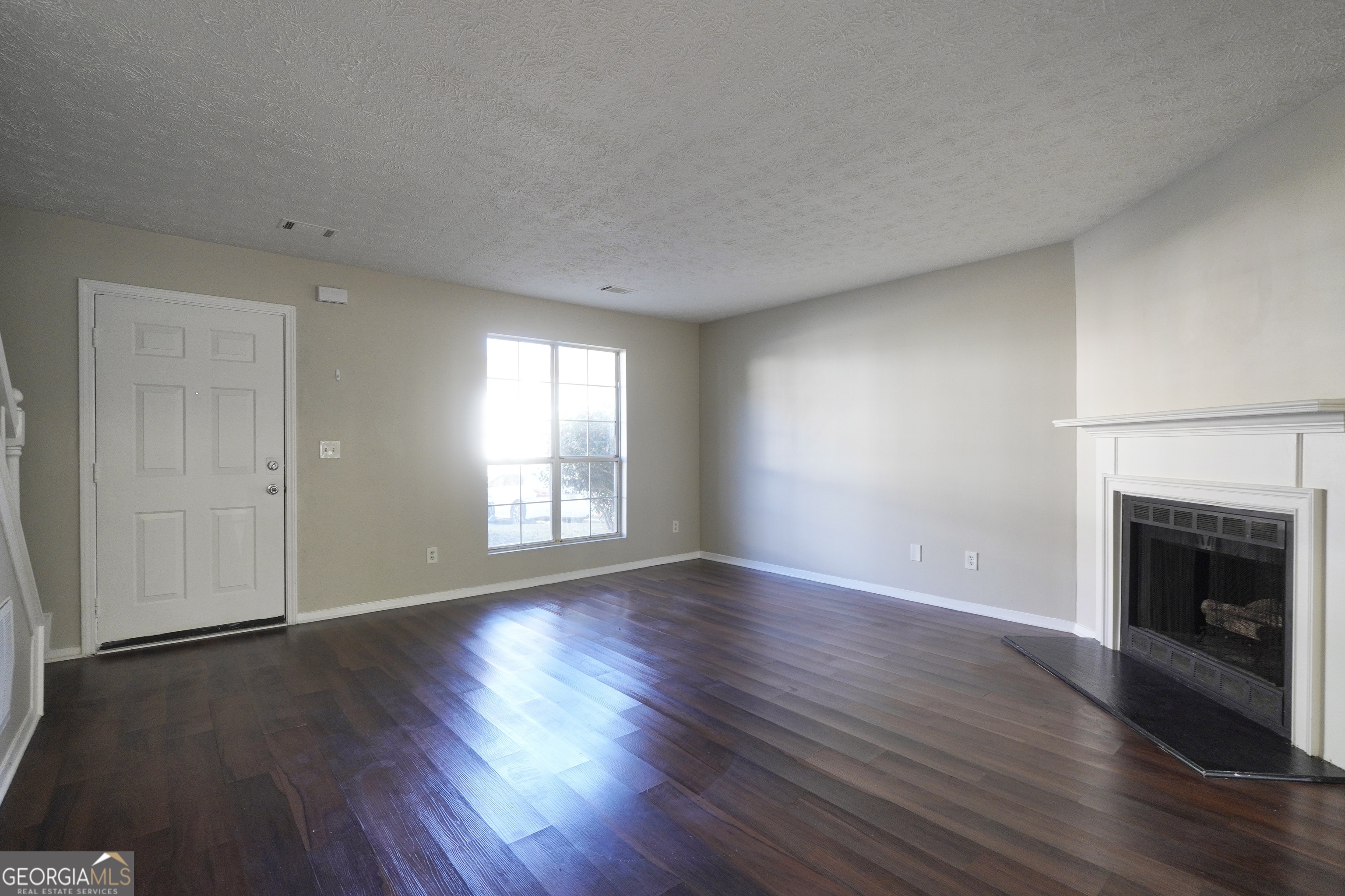 5702 Wells Circle Stone Mountain, GA 30087 - Photo 11 of 29 an empty room with wooden floor fireplace and windows