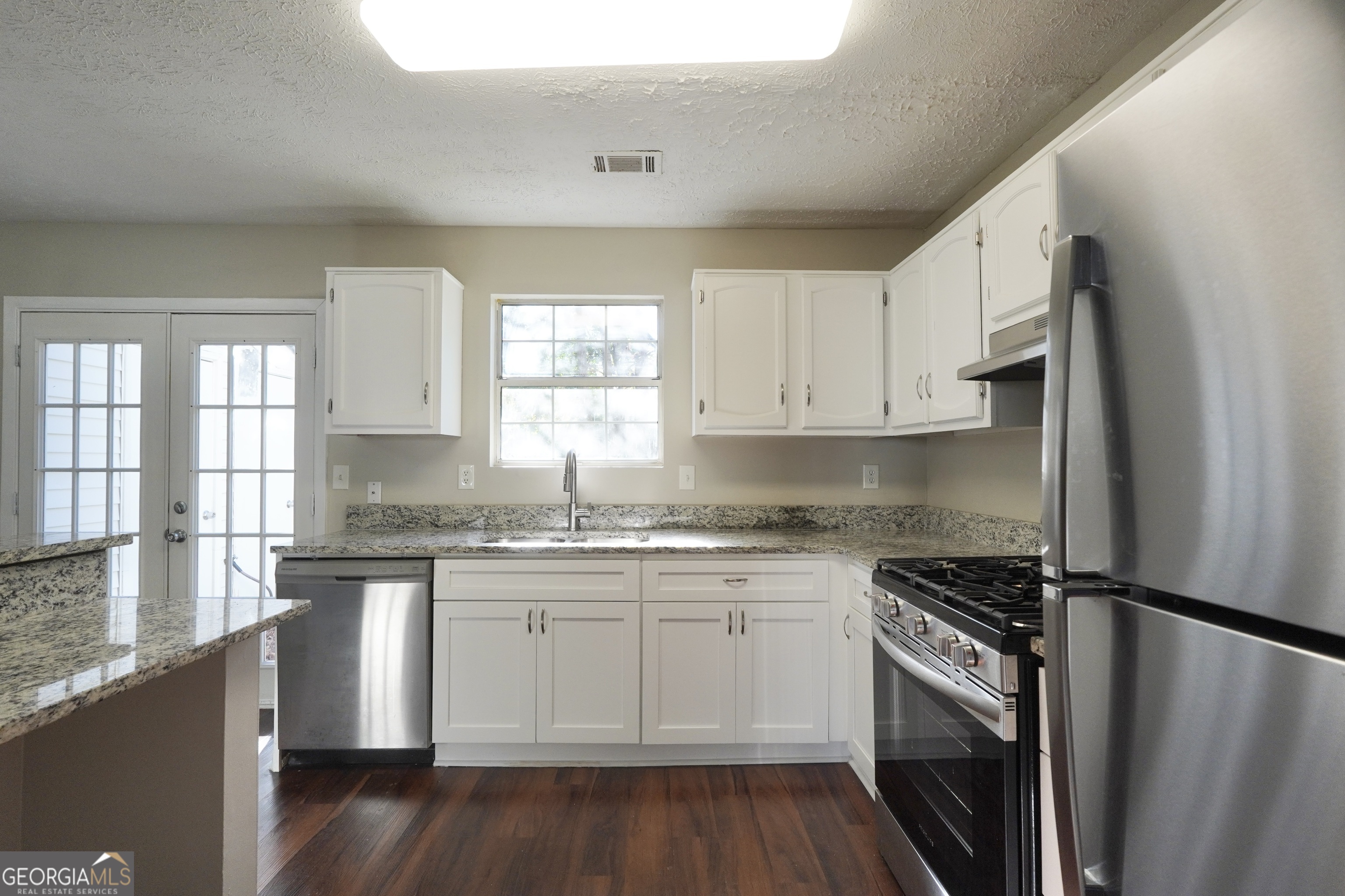 5702 Wells Circle Stone Mountain, GA 30087 - Photo 4 of 29 a kitchen with stainless steel appliances granite countertop a stove a sink dishwasher a refrigerator and white cabinets with wooden floor