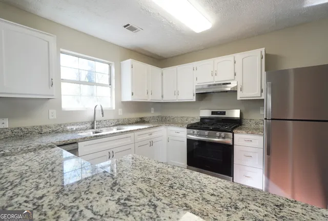a kitchen with granite countertop a sink stainless steel appliances and cabinets