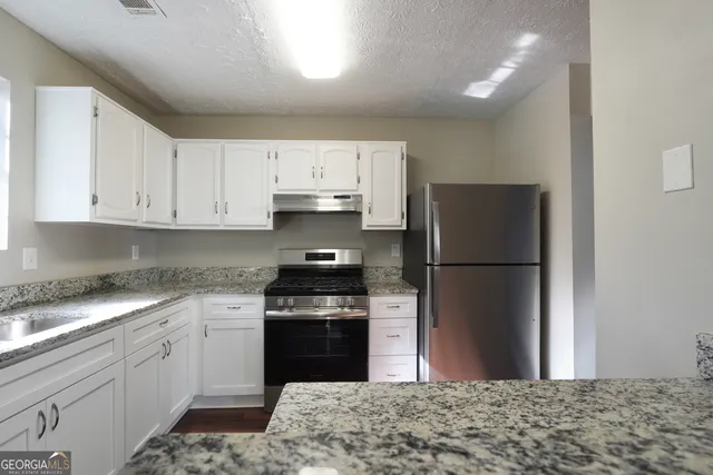 a kitchen with a refrigerator sink and cabinets