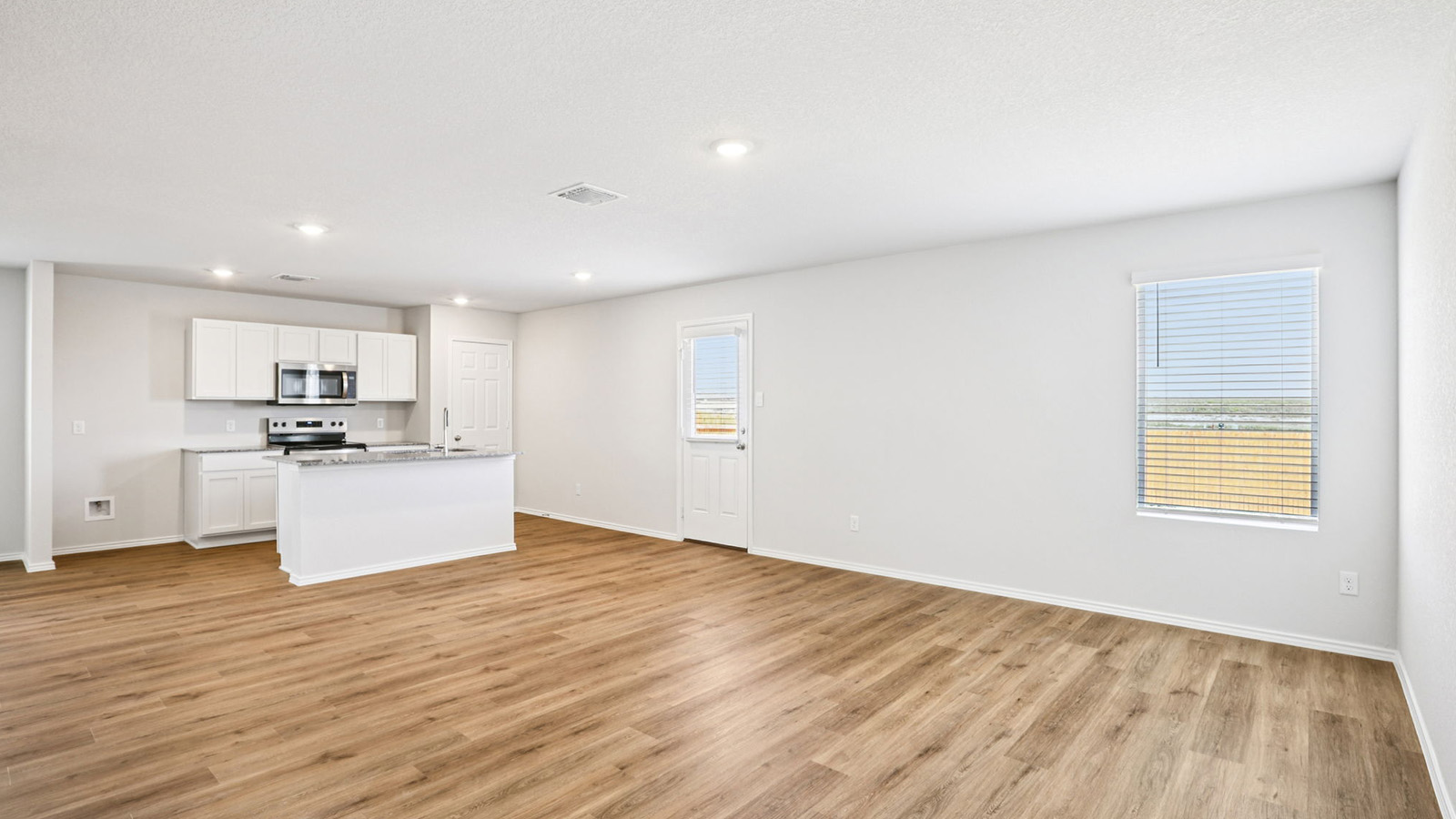 133 Wyatt Way Jarrell, TX 76537 - Photo 12 of 32 Open-concept living area featuring wood-finish flooring, recessed lighting, and a kitchen with white cabinetry, stainless steel appliances, and a central island with a countertop