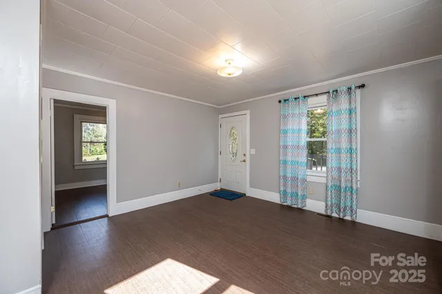 a view of an empty room with window and wooden floor