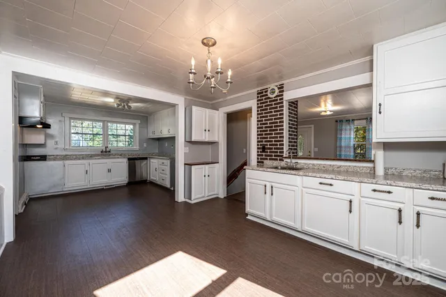 a kitchen with granite countertop white cabinets white appliances a sink and a window