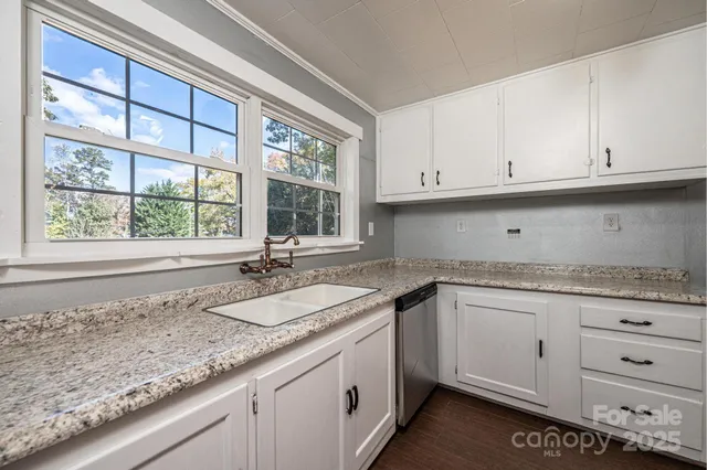 a kitchen with granite countertop white cabinets and a window