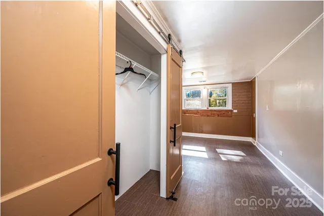 a view of an empty room with wooden floor and windows