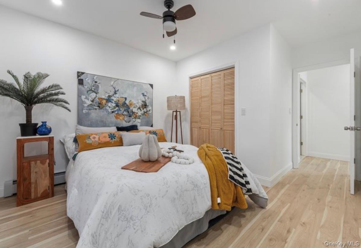 136-18 221st Street Queens, NY 11413 - Photo 12 of 23 Bedroom featuring a closet, a ceiling fan, light wood-style floors, recessed lighting, and a baseboard heating unit