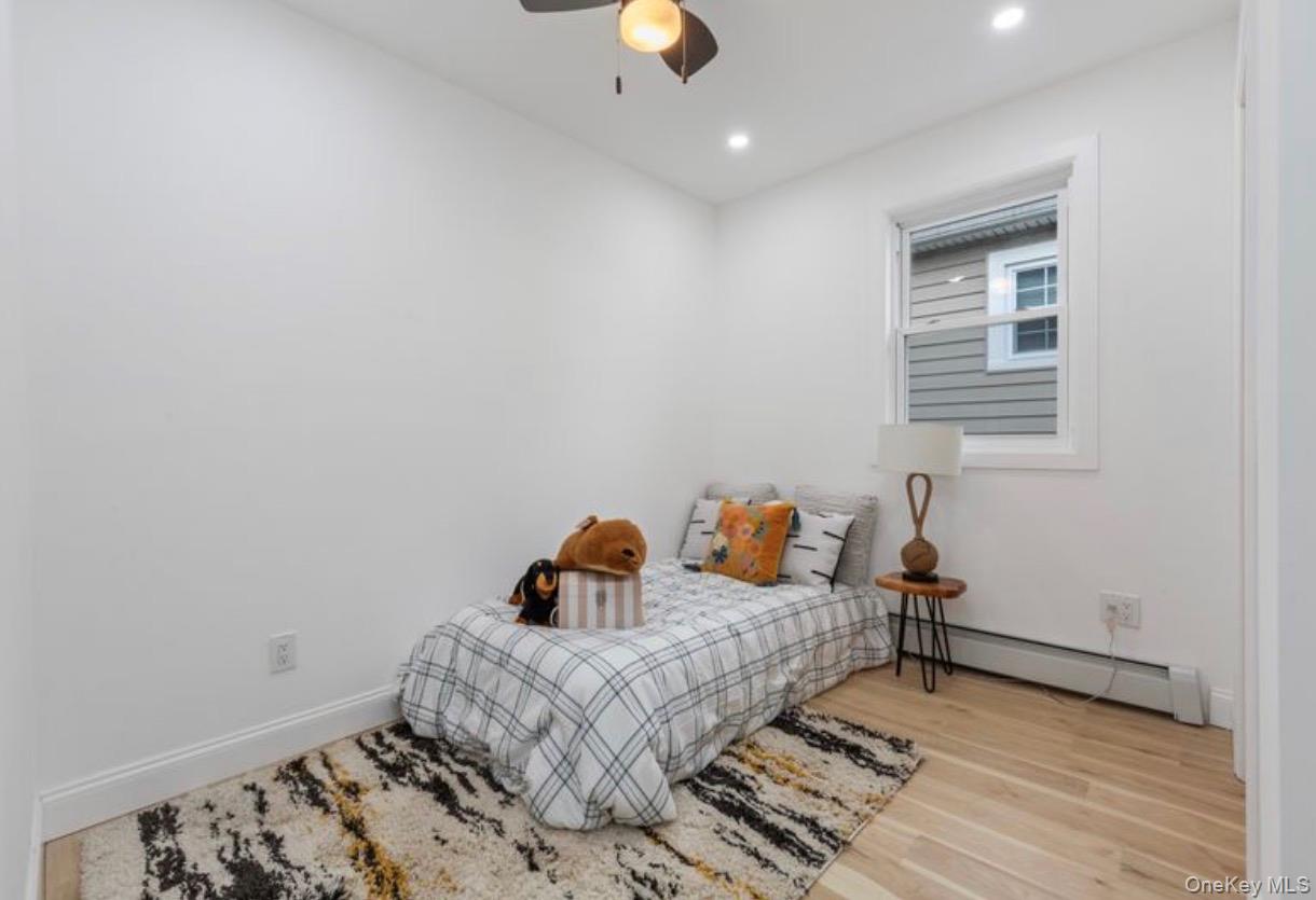 136-18 221st Street Queens, NY 11413 - Photo 15 of 23 Bedroom featuring baseboard heating, light wood-type flooring, ceiling fan, and recessed lighting