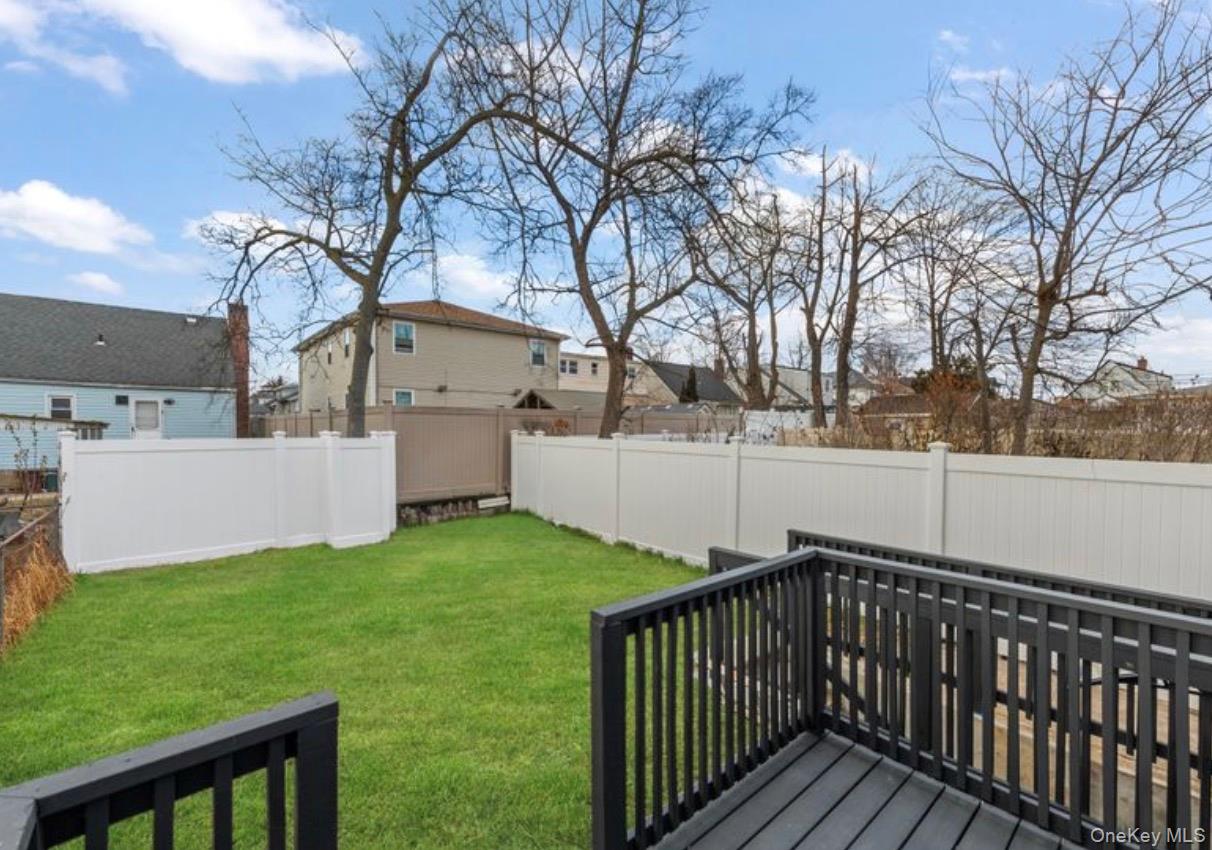 136-18 221st Street Queens, NY 11413 - Photo 21 of 23 Fenced backyard with a wooden deck and a residential view