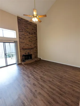 an empty room with wooden floor fireplace and chandelier