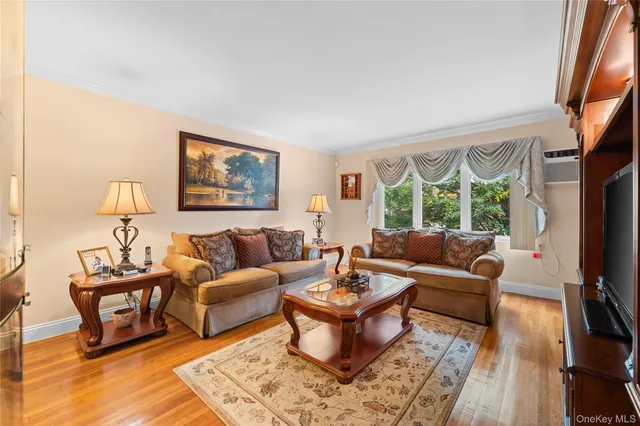 a living room with furniture two large window and a flat screen tv