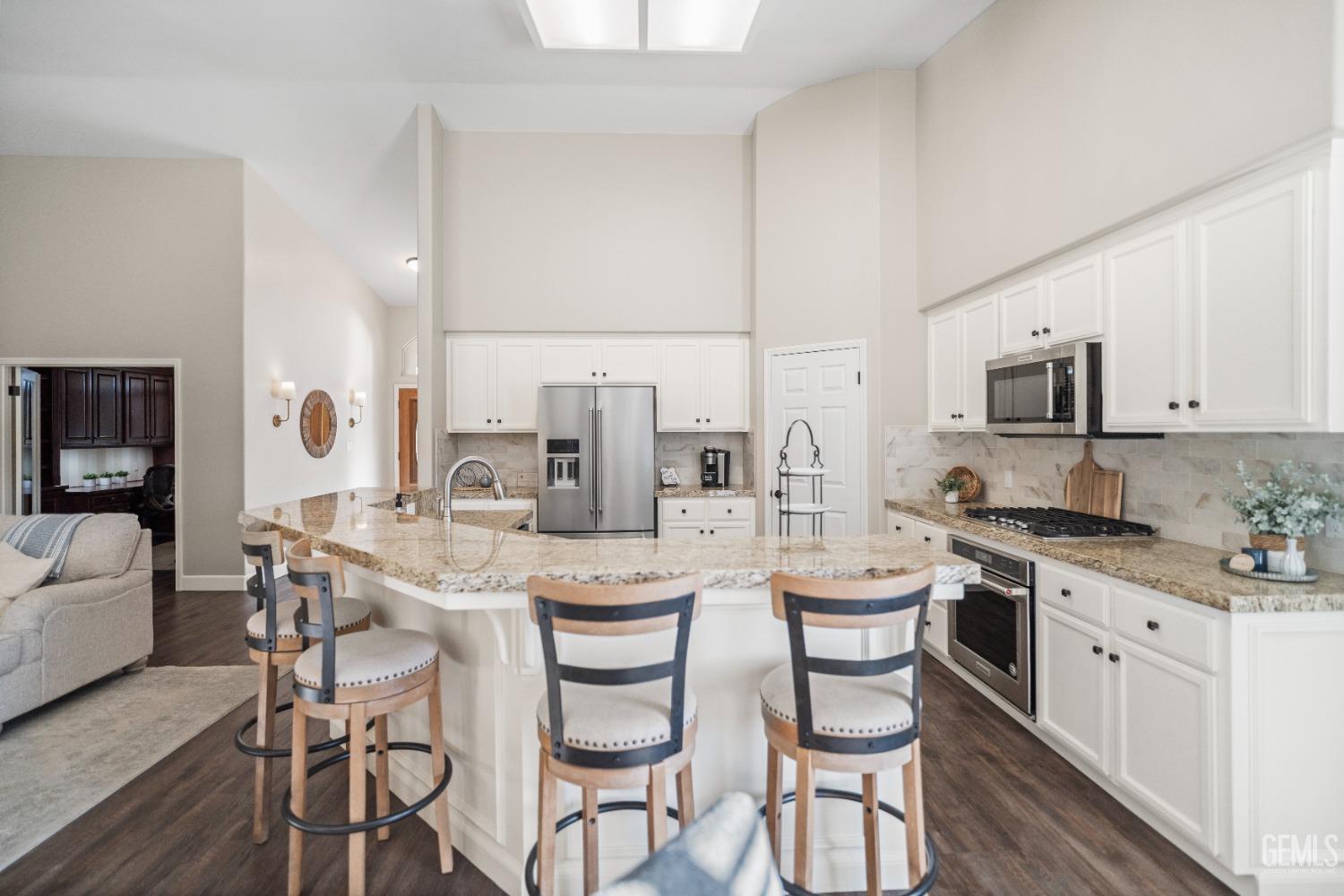 Undisclosed Address Bakersfield, CA 93308 - Photo 11 of 37 a large kitchen with a table chairs stove and white cabinets