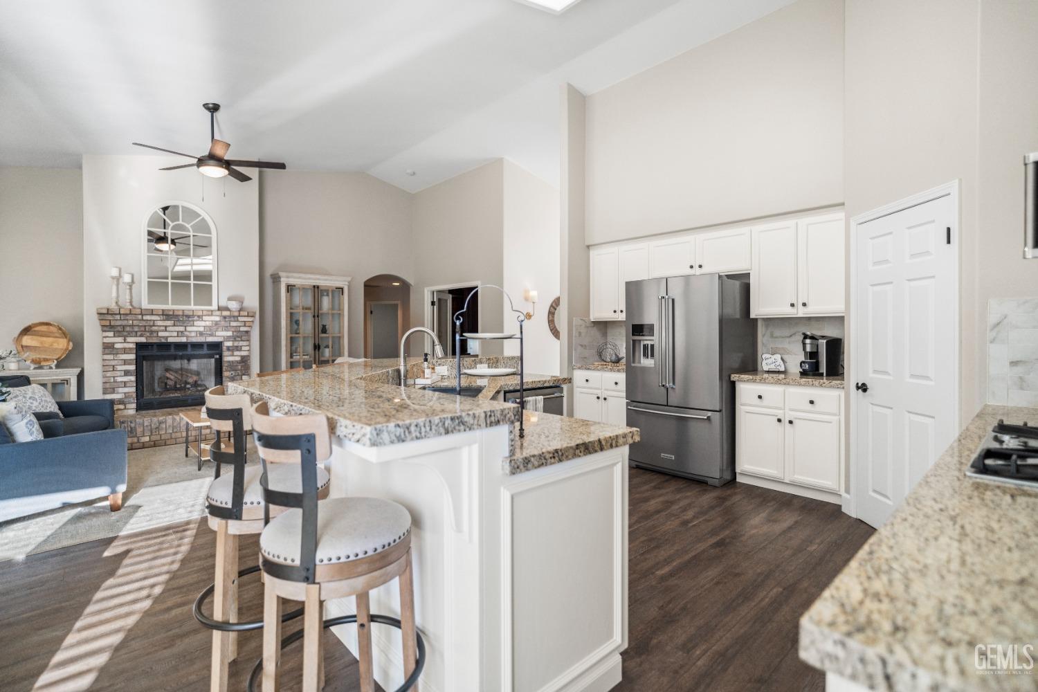 Undisclosed Address Bakersfield, CA 93308 - Photo 12 of 37 a kitchen with stainless steel appliances kitchen island granite countertop a refrigerator a stove and white cabinets with wooden floor