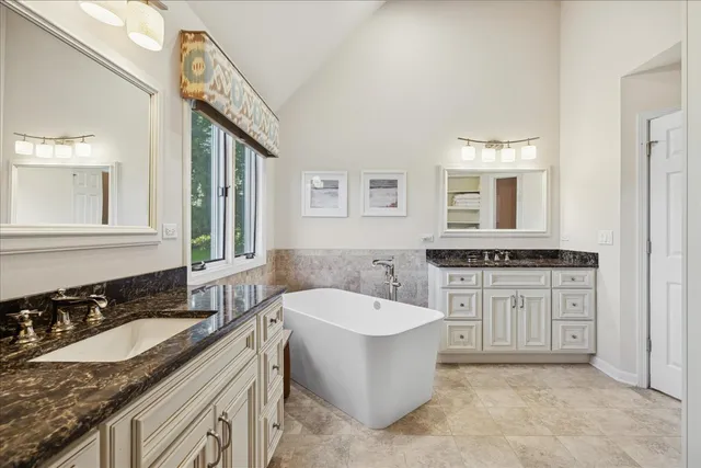 a spacious bathroom with a granite countertop tub sink and mirror