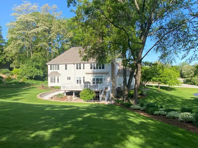 a view of a house with a big yard and large trees