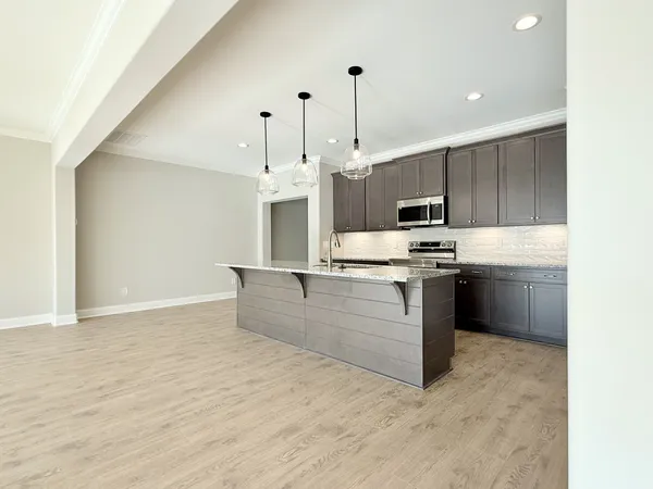 a kitchen with stainless steel appliances kitchen island granite countertop a stove a sink and a refrigerator