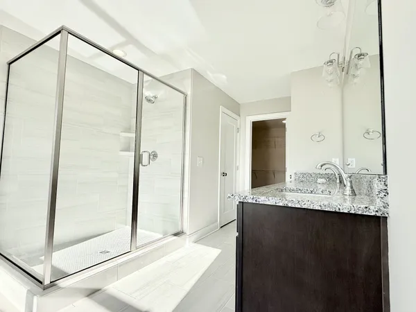 a bathroom with a granite countertop sink a mirror and shower