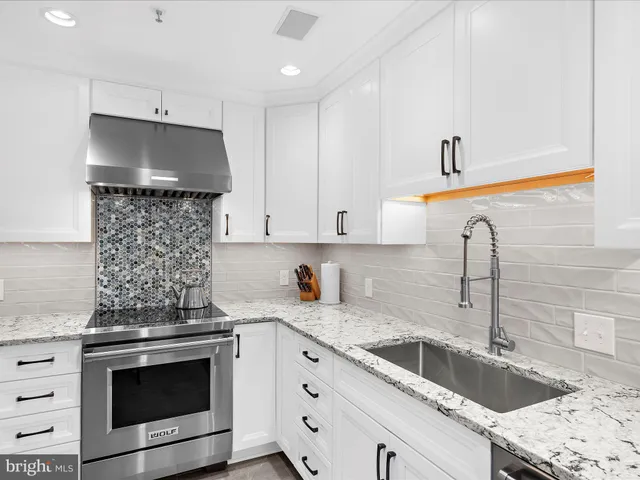 a kitchen with granite countertop a sink stove and cabinets