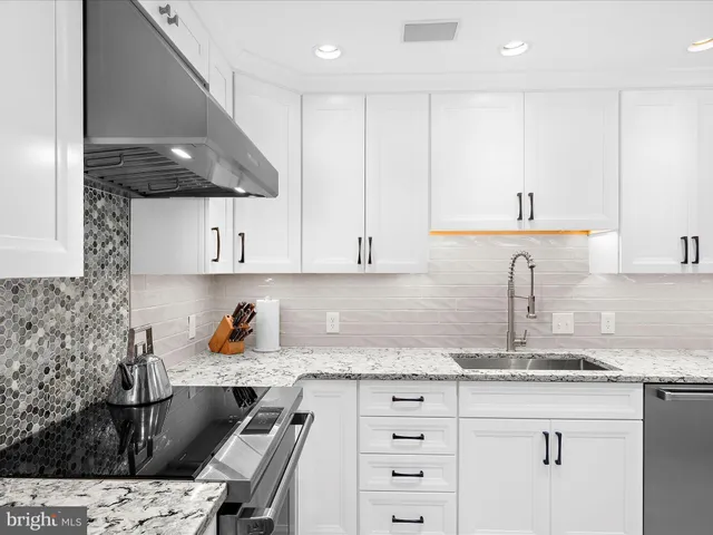 a kitchen with granite countertop a sink a stove and cabinets