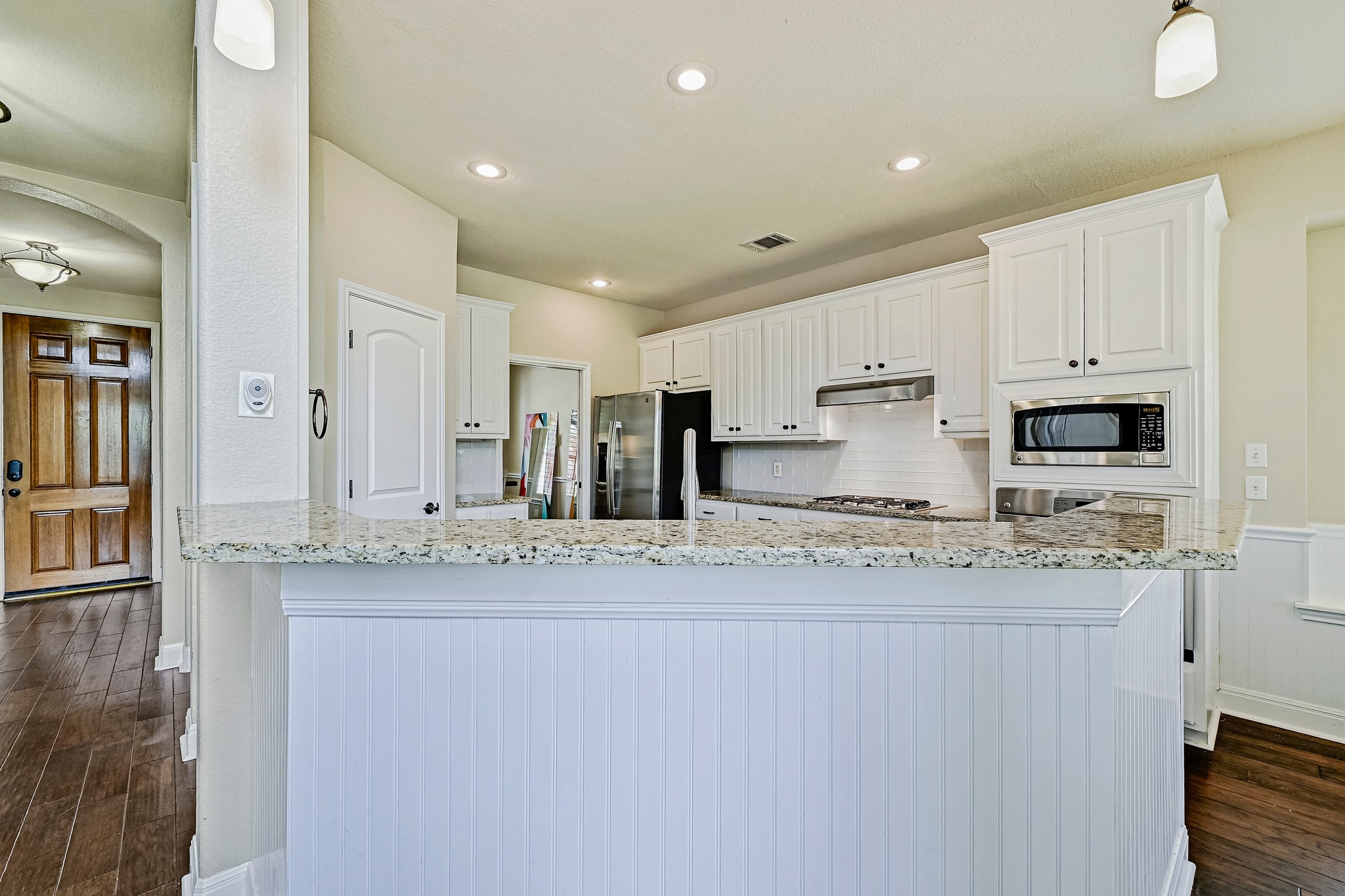 2408 Amen Corner Road Pflugerville, TX 78660 - Photo 12 of 40 Kitchen featuring white cabinetry, light-toned countertops, a built-in microwave, and a subway tile backsplash