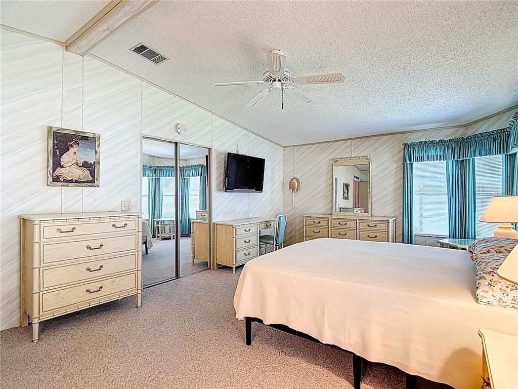 14761 Rialto Avenue Brooksville, FL 34613 - Photo 9 of 23 a spacious bedroom with a bed a couch and a flat tv screen