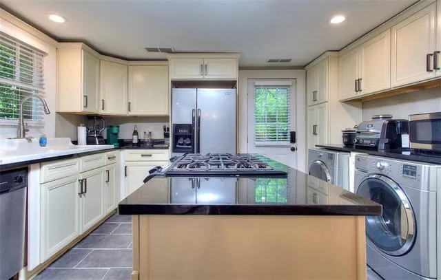 a kitchen with kitchen island granite countertop a sink a stove cabinets and a refrigerator