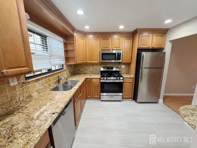 a kitchen with kitchen island granite countertop a refrigerator a sink a stove top oven and a refrigerator