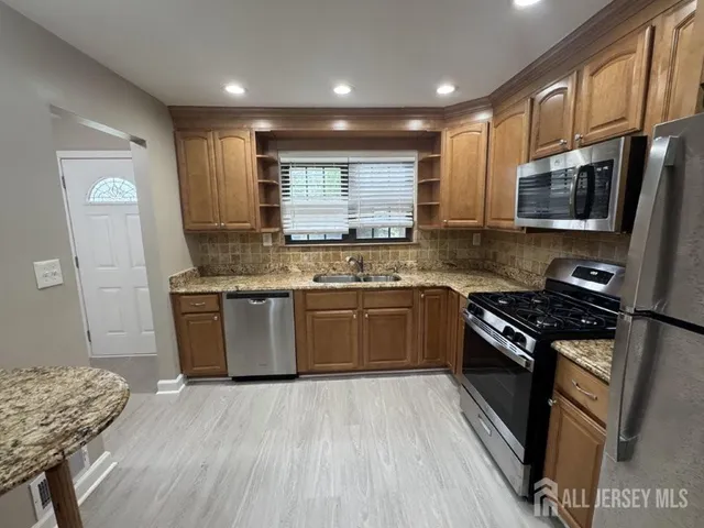 a kitchen with stainless steel appliances granite countertop a stove a sink dishwasher a microwave oven and a refrigerator with wooden floor