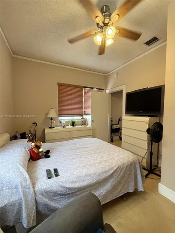 a bedroom with a bed and a flat tv screen on the dresser