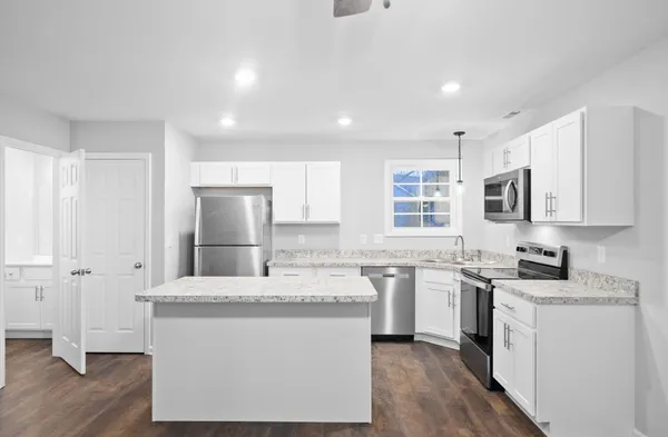 a large kitchen with stainless steel appliances granite countertop a stove a sink dishwasher and a refrigerator with wooden floor