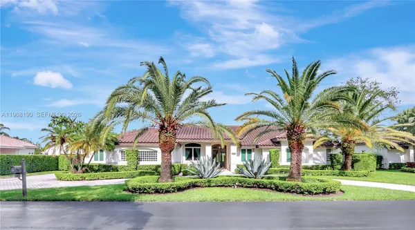 a front view of a house with a garden and trees