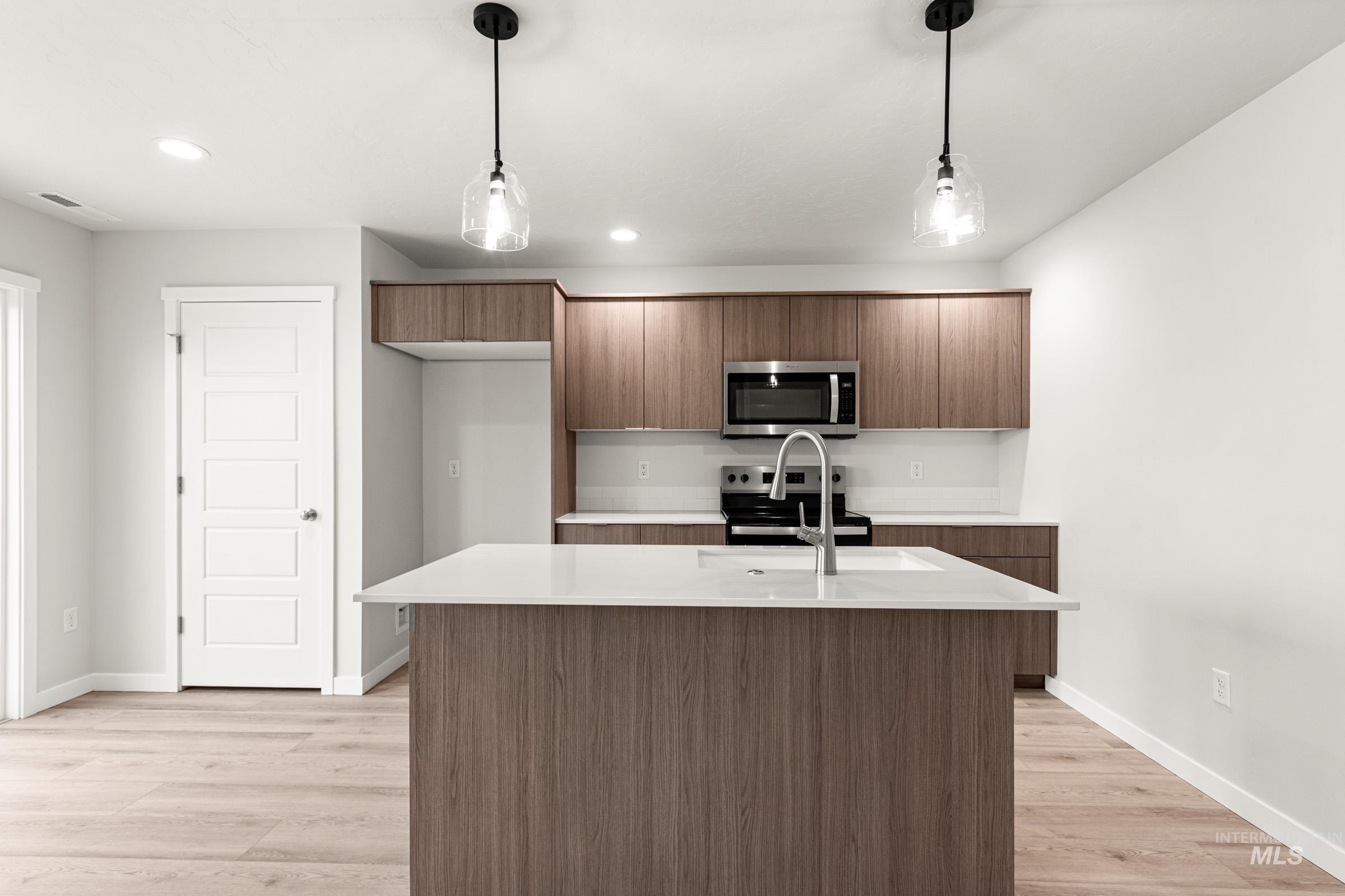 10824 Rutland Street Caldwell, ID 83605 - Photo 3 of 20 Kitchen featuring stainless steel appliances, hanging light fixtures, modern cabinets, light wood-style floors, and wood finish cabinetry