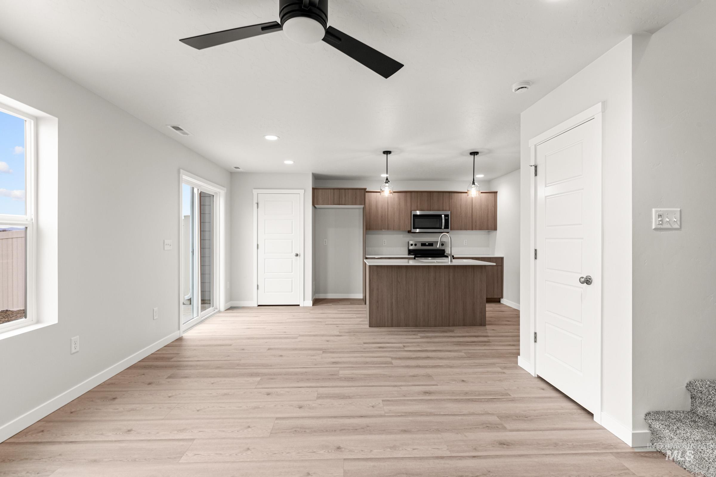 10824 Rutland Street Caldwell, ID 83605 - Photo 20 of 20 Kitchen featuring light countertops, ceiling fan, open floor plan, a kitchen island with sink, and light wood finished floors