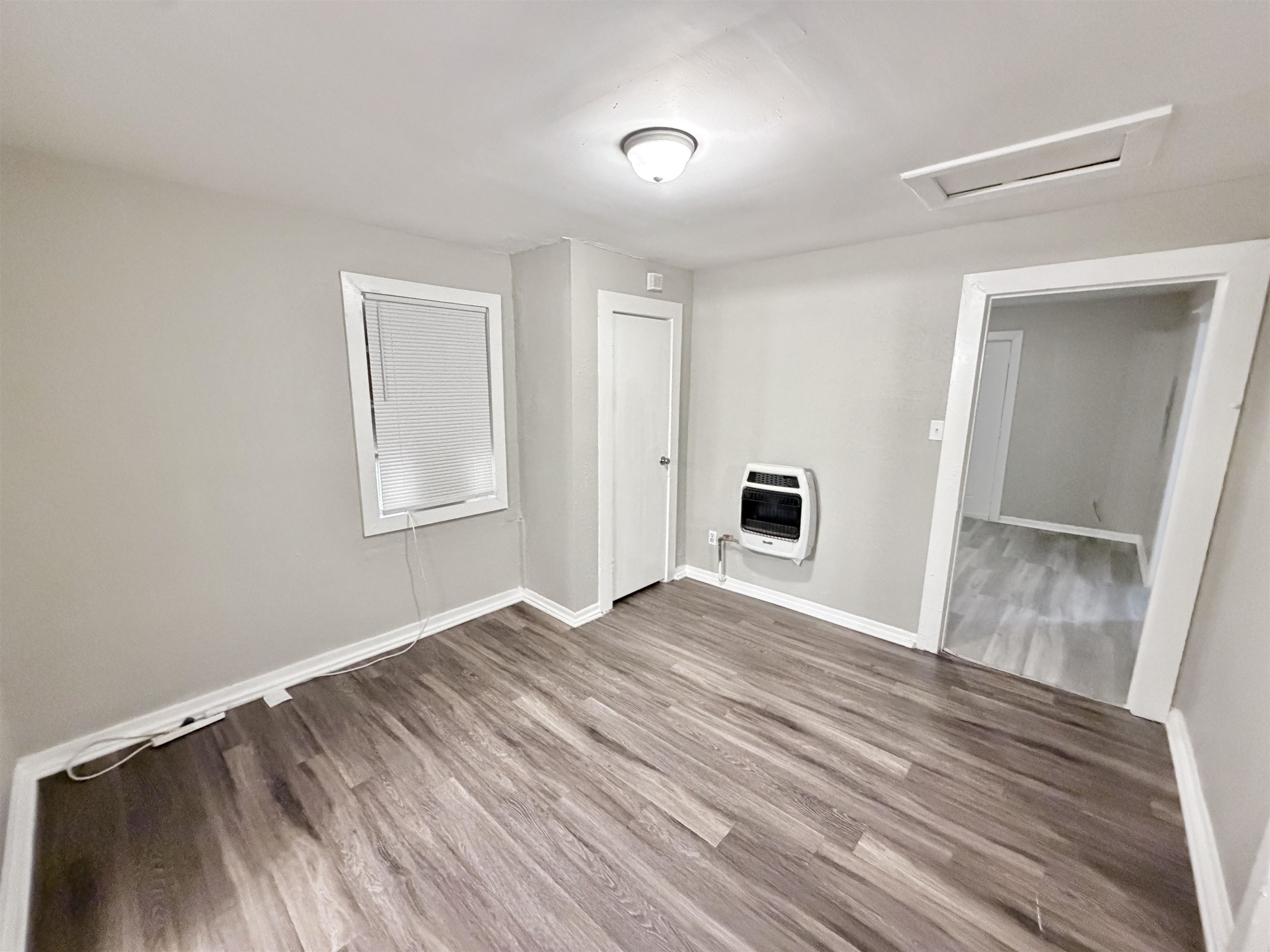 3100 Travis Road Memphis, TN 38109 - Photo 8 of 16 Wood-finish flooring throughout, light gray wall paint, and a wall-mounted heating unit