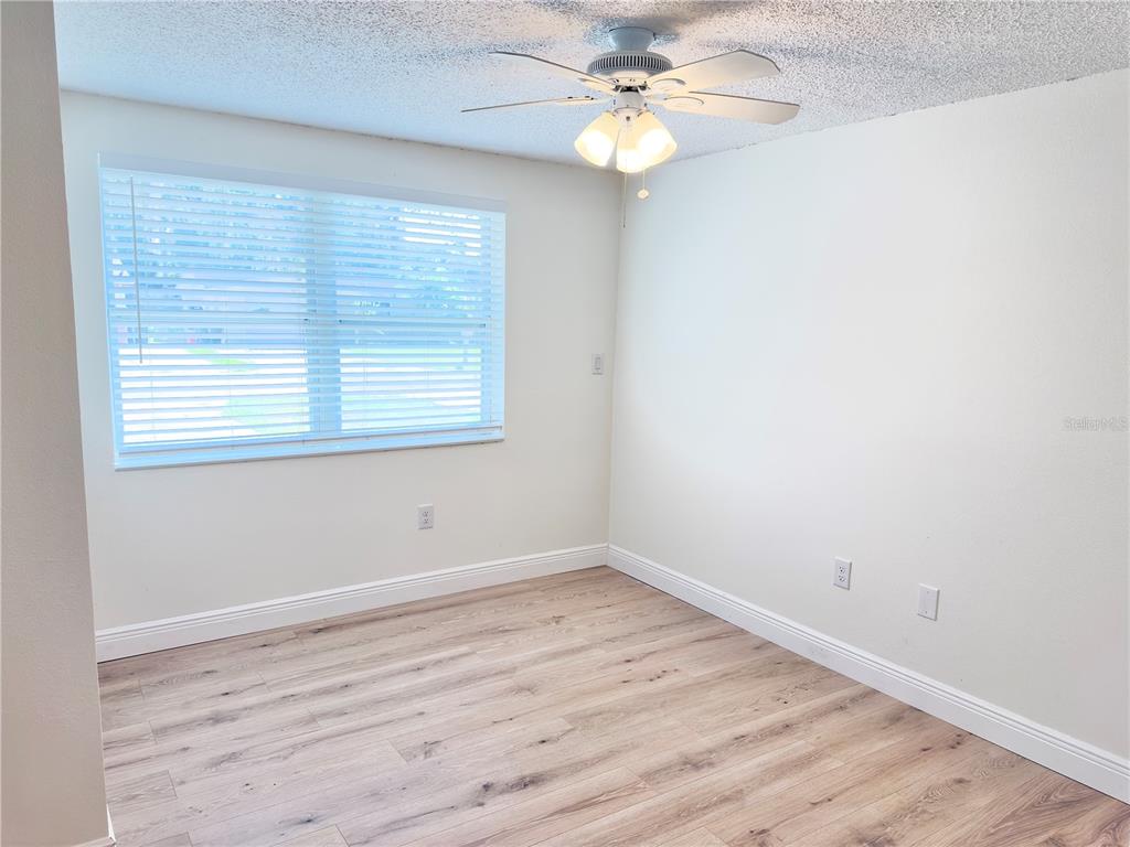 5701 Quist Drive Port Richey, FL 34668 - Photo 17 of 53 an empty room with wooden floor fan and windows