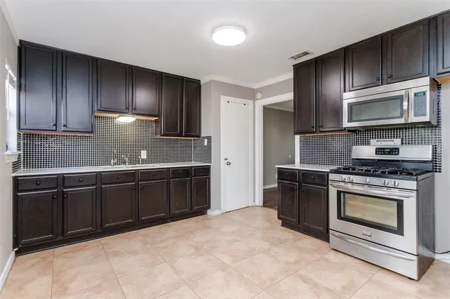 a kitchen with granite countertop wooden cabinets stainless steel appliances and a sink