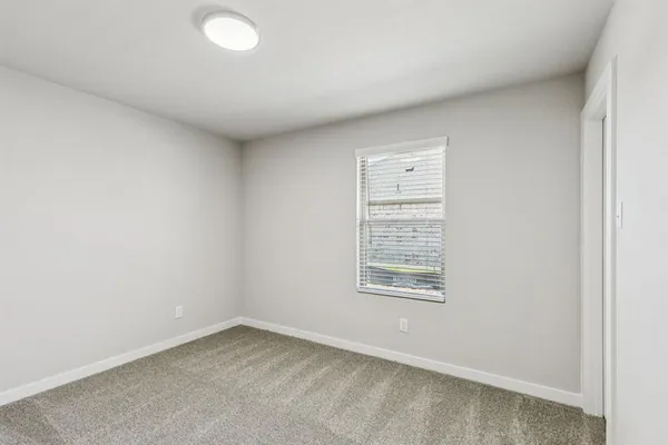 an empty room with a window and a bathroom