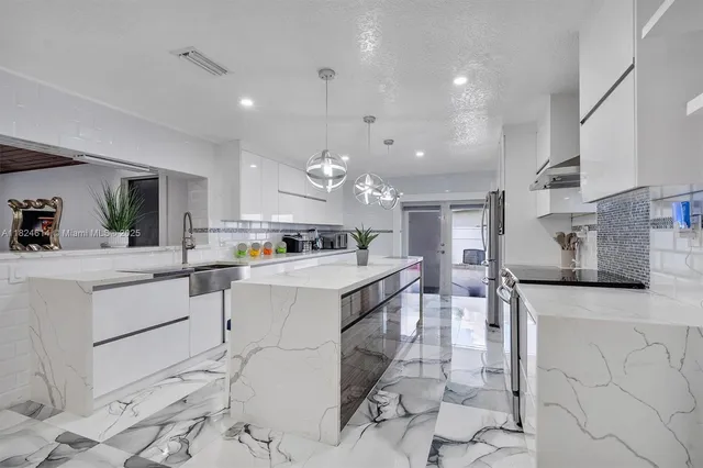 a large white kitchen with a lot of counter space and appliances